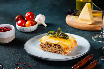 Piece of tasty hot lasagna on dark background. Traditional italian lasagna. Italian food. Close up lasagna. Bolognese sauce. Bechamel sauce. Still life of food. Homemade meat lasagna.