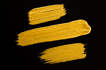 Acrylic gold paint brush on a black background