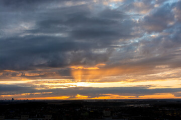 Beautiful sunset sky over the city. The sun over city houses. Blue sky and yellow clouds. Wide panorama.