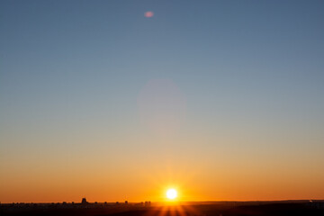 Beautiful sunset sky over the city. The sun over city houses. Bird's-eye. Blue sky and yellow clouds. Wide panorama.