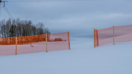 Orange perforated plastic foil barriers against snow in farmland. This protects the snow cover on agricultural fields.