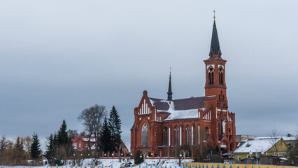 Catholic church of St. Anthony of Padua in Pastavy in winter. Monument of architecture in the neo-Gothic style. - obrazy, fototapety, plakaty