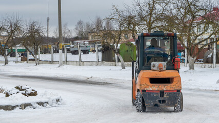 The forklift truck on the winter street. Outdoor forklift transporting cargo on the openair...