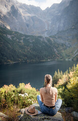 Naklejka na ściany i meble Young woman on a hiking trip sitting on a rock