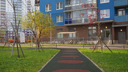 A path to an apartment building, a landscaped courtyard, young trees along the alley. Concept for...