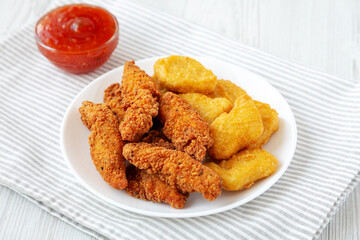Homemade Nuggets and Chicken Tenders with Sweet and Sour Sauce on a white wooden background, side view.
