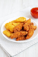 Homemade Nuggets and Chicken Tenders with Sweet and Sour Sauce on a white wooden background, low angle view.