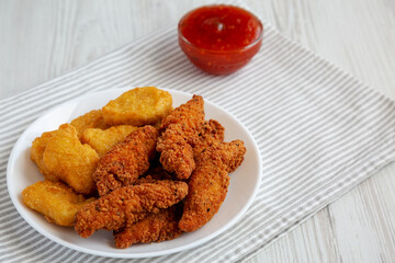 Homemade Nuggets and Chicken Tenders with Sweet and Sour Sauce on a white wooden background, side view. Copy space.