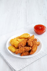 Homemade Nuggets and Chicken Tenders with Sweet and Sour Sauce on a white wooden background, side view. Copy space.