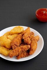 Homemade Nuggets and Chicken Tenders with Sweet and Sour Sauce on a black background, side view. Space for text.