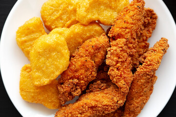 Homemade Nuggets and Chicken Tenders with Sweet and Sour Sauce on a black background, top view. Overhead, from above, flat lay.