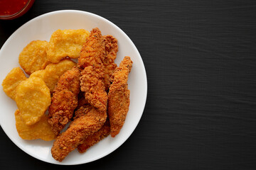 Homemade Nuggets and Chicken Tenders with Sweet and Sour Sauce on a black background, top view. Overhead, from above, flat lay. Copy space.