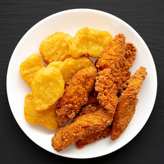 Homemade Nuggets and Chicken Tenders with Sweet and Sour Sauce on a black background, top view. Overhead, from above, flat lay.