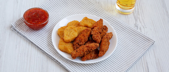 Homemade Nuggets and Chicken Tenders with Sauce and Beer, side view.