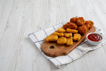 Homemade Crispy Fried Chicken Wings and Nuggets with Sweet and Sour Sauce on a rustic wooden board, side view. Copy space.