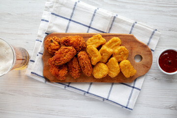 Homemade Crispy Fried Chicken Wings and Nuggets on a rustic wooden board, top view. Flat lay, from above, overhead.