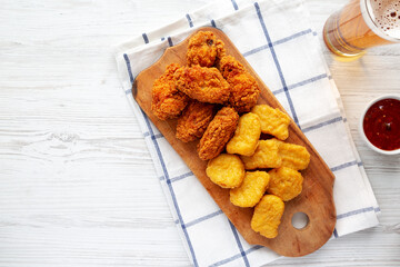 Homemade Crispy Fried Chicken Wings and Nuggets on a rustic wooden board, top view. Flat lay, from above, overhead. Space for text.