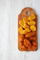 Homemade Crispy Fried Chicken Wings and Nuggets on a rustic wooden board, top view. Flat lay, from above, overhead. Space for text.
