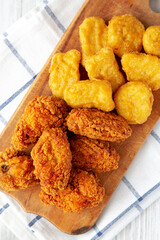 Homemade Crispy Fried Chicken Wings and Nuggets with Sweet and Sour Sauce on a rustic wooden board, top view. Flat lay, from above, overhead.