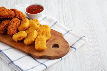 Homemade Crispy Fried Chicken Wings and Nuggets with Sweet and Sour Sauce on a rustic wooden board, low angle view.