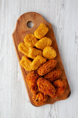 Homemade Crispy Fried Chicken Wings and Nuggets on a rustic wooden board, top view. Flat lay, from above, overhead.