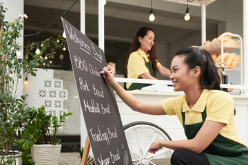Smiling young woman filling board withu of food cart her family owns © DragonImages