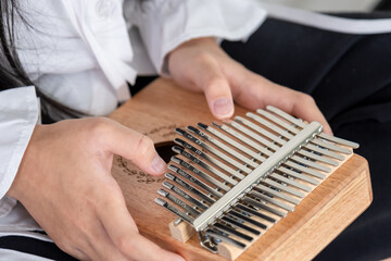 Hand of an Asian girl playing a wooden Kalimba instrument