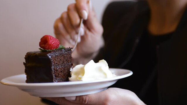Woman eats a chocolate cake with extra cream