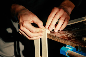 Carpenter at workbench nails down small wooden box. Hands of worker with old axe. Authentic workflow in carpentry workshop. Production of order. Small business.