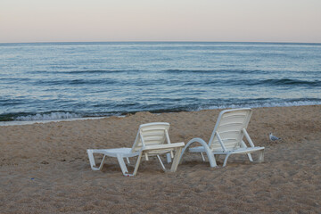 Two sunbeds on a sandy calm beach with turquoise sea water and white sand