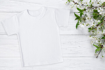 Spring t-shirt mockup with blossom cherry, flat lay on wood background with copy space. Easter,...