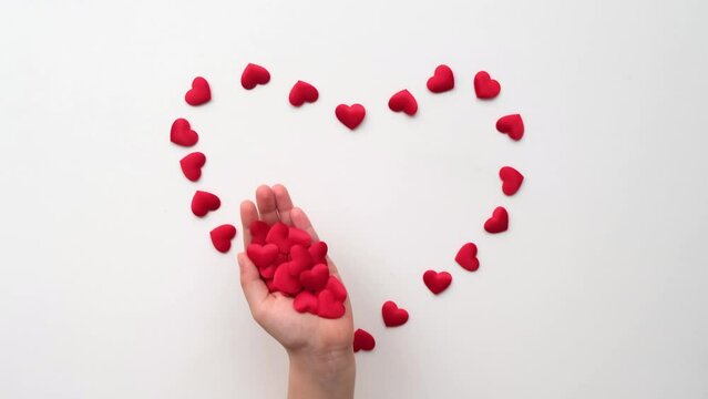 Heart made of shiny red small decorative hearts appearing on a white background with child hands
