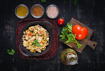 Rice with chicken and vegetables in bowl on dark background. Diet menu. Lunch. Top view