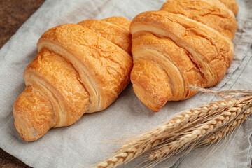 Two croissants with spikelet of wheat on napkin
