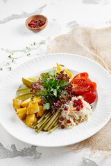 Appetizers from pickled vegetables in white stone background. Authentic food in restaurant menu. Mix from salted tomatoes, cucumber,  pickled pepper, sauerkraut. Assorted from marinated vegetables.