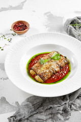 Eggplant rolls stuffed with tomato and cheese. Baked eggplant and cheese rollatini. Eggplant appetizer in white plate on stone background. Plant-based menu.