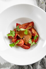 Roasted beef tongue with gravy and dried tomatoes. Meat dish from beef tongue and vegetables garnish. Delicatessen main course - ox tongue.