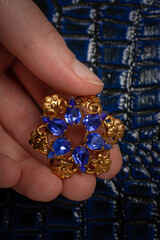 holding a gold brooch on a leather background