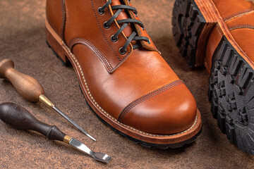 Handcrafted brown leather shoes with cobbler tools on the backgound