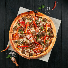 Homemade pizza with meatball on black wood background.  American pizza with meat and cheese. Italian pizza  in rustic style. Junk food on dark backgroundp87