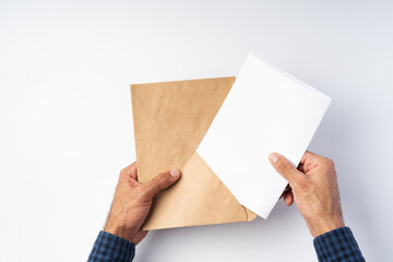 Obraz premium Top view of male hands hold (open) an envelope above white background