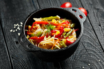 Vegetarian stir fried noodles on dark background. Asian vegan pasta on wok. Veggie wok on black wooden table. Spaghetti with vegetables on chinese style. Thai food menu..