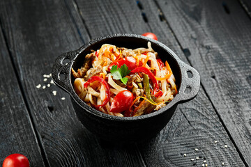 Japanese stir fryed udon noodles in wok. Udon noodle with beef and vegetables on wooden background....