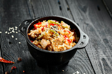 Chicken fried rice on wok. Asian food - fried rice with vegetables, egg and chicken on dark table. Wok menu on black wood background. Traditional chinese food.
