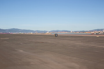 Fototapeta na wymiar On the runway in Gibraltar with some installations from the harbor of Algeciras. Distant objects are blurred due to the heat coming from the concrete