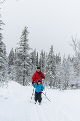 Young cross country skier in front of mother, Sweden.