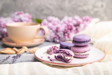 Fototapeta na wymiar Purple macarons or macaroons cakes with cup of coffee on a gray wooden background. Side view, selective focus.