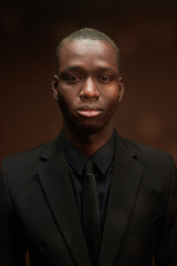 Fototapeta premium Young serious businessman of African ethnicity in black tie, shirt and jacket standing in front of camera and looking at you