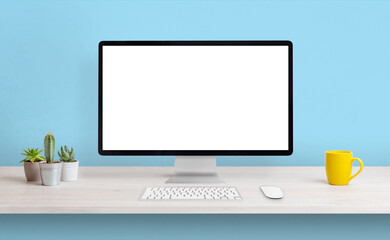Computer display with white isolated screen for presentation on work desk. Clean composition with coffee mug and plants. Blue wall in background