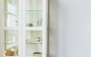 Fototapeta na wymiar Cabinet filled with decoration elements. Glass door. White wood.